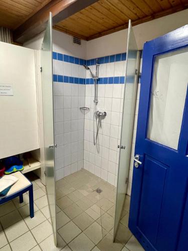a bathroom with a shower with a blue door at Historisches Reetdach-Haus - bis zu 21 Personen in Großefehn 