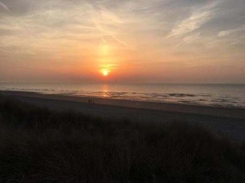 a sunset on the beach with the sun setting at Appartement Duin225 in Bredene