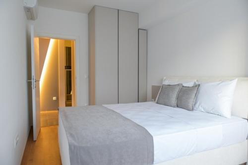 a white bed in a white bedroom with a door at Luxury living by Dazzie in Skopje