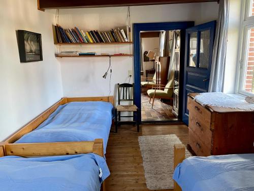a bedroom with two beds and a door with a chair at Historisches Reetdach-Haus - bis zu 21 Personen in Großefehn 