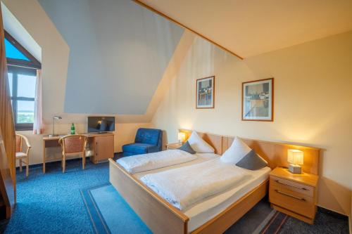 a bedroom with a bed and a desk and a chair at BurgStadt-Hotel in Kastellaun