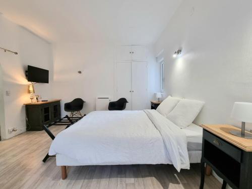 una camera bianca con un grande letto e due sedie di La Chambre Bleue - Chambre avec salle de bain ad Argenton-sur-Creuse