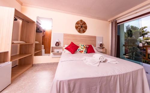 a bedroom with a large white bed with red pillows at Pousada Terra Mar Way in Barra Grande