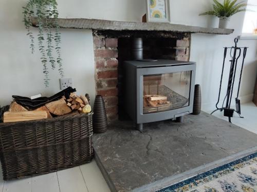 a living room with a fireplace and a basket of logs at Trevose, sea views in Port Isaac