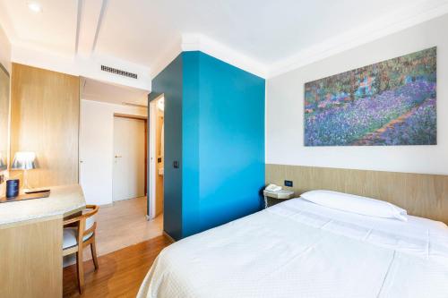 a bedroom with a blue accent wall and a bed at Hotel Metropole Suisse in Como