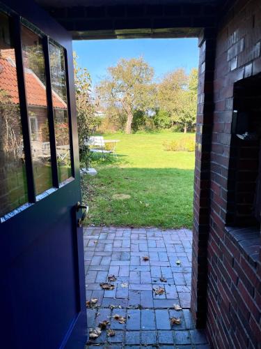 an open door to a yard with a picnic table at Historisches Reetdach-Haus - bis zu 21 Personen in Großefehn 
