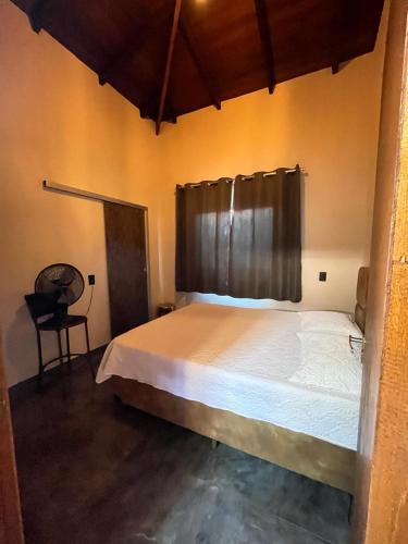 a bedroom with a large bed and a chair at Casa Veiga in Pirenópolis