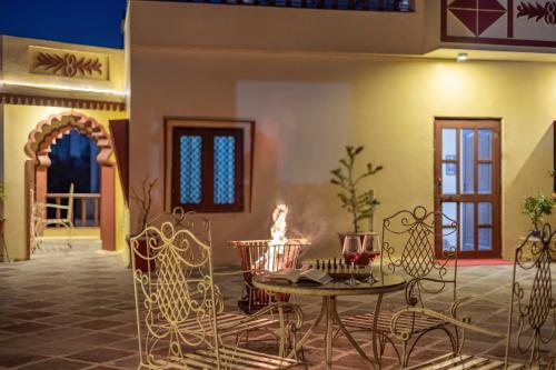 a room with a table and chairs and a fireplace at Alaya Stays 2 BHK With Garden & Outdoor Area - Abhimanyu Mansion Topaz in Udaipur