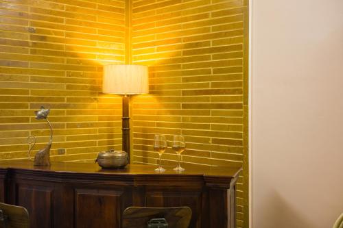 a table with two wine glasses and a lamp at Alaya Stays 2 BHK With Garden & Outdoor Area - Abhimanyu Mansion Topaz in Udaipur