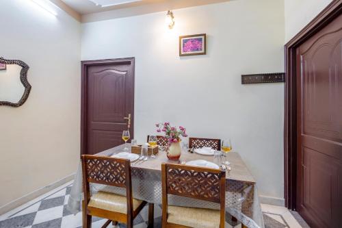 a dining room with a table and chairs with wine glasses at Alaya Stays 2 BHK With Garden & Outdoor Area - Abhimanyu Mansion Topaz in Udaipur