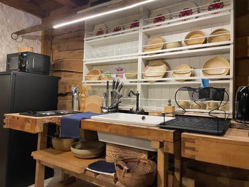 a kitchen with a sink and shelves with dishes at Fészek Vendégház in Szandaváralja