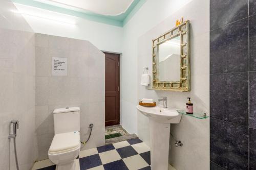a bathroom with a toilet and a sink and a mirror at Alaya Stays 2 BHK With Garden & Outdoor Area - Abhimanyu Mansion Topaz in Udaipur