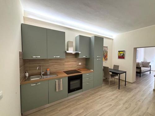 a kitchen with green cabinets and a dining room at A due passi da Piazza Cavalli in Piacenza