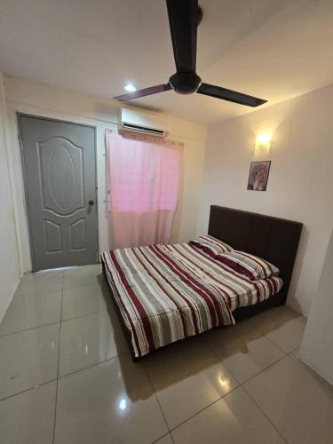 a bedroom with a bed with a striped blanket and a door at Close II-Jangan Tempah in Kinarut