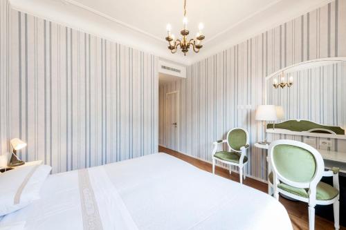 a bedroom with a bed and a desk and chairs at Hotel Metropole Suisse in Como