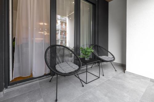 two chairs and a table in front of a window at Apartment Simpatico in Novi Sad