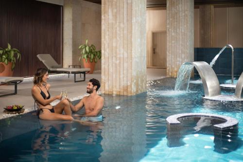 a man and a woman sitting in a swimming pool at Live Aqua Punta Cana - All Inclusive - Adults Only in Punta Cana