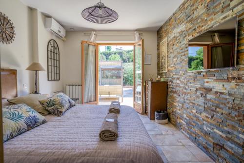 une chambre avec un grand lit et un mur de briques dans l'établissement Villa Golf les Cigales, à Mouans-Sartoux