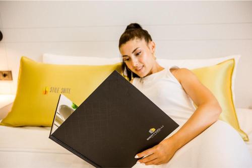 a woman laying on a bed holding a laptop at Stile Suite Family Hotel in Antalya