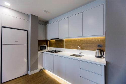 a white kitchen with a sink and a refrigerator at Stile Suite Family Hotel in Antalya