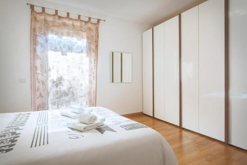 Un dormitorio con una cama blanca y una ventana. en Villa Loncrino - Fine Living, en Torri del Benaco