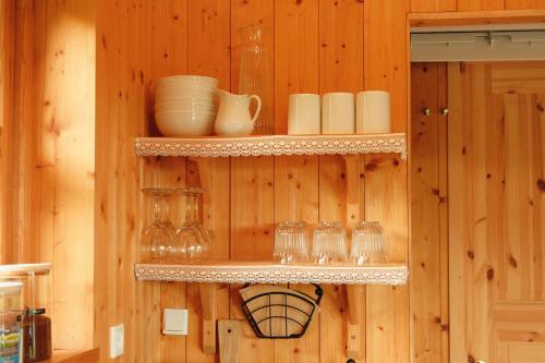 a wooden wall with shelves with glasses and dishes at Múlafossur Cottages by famous waterfall in Gásadalur in Gásadalur