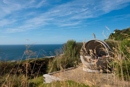 a wicker chair sitting on a hill overlooking the ocean at Gara Rock in Salcombe