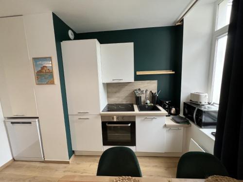 - une cuisine avec des placards blancs et un mur vert dans l'établissement Le Duplex des remparts, 4-6Pers, à Boulogne-sur-Mer