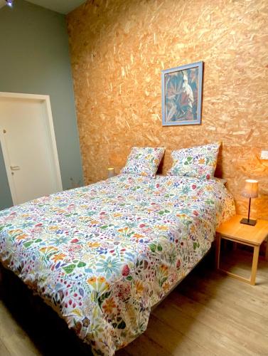a bedroom with a bed with a comforter on it at La Demoiselle ô Bois - Gîte nature et confort aux portes de Chimay in Seloignes
