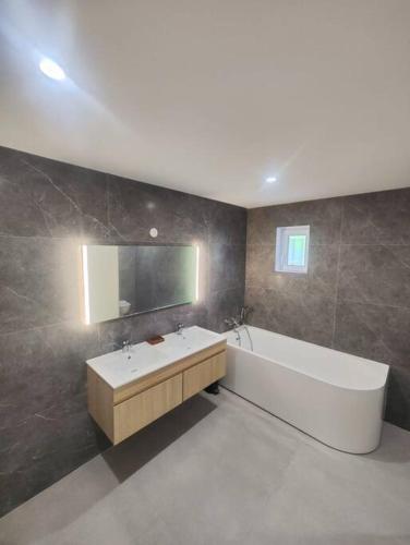 une salle de bain avec une baignoire, un lavabo et un miroir dans l'établissement Villa du Golf, à Montboucher-sur-Jabron