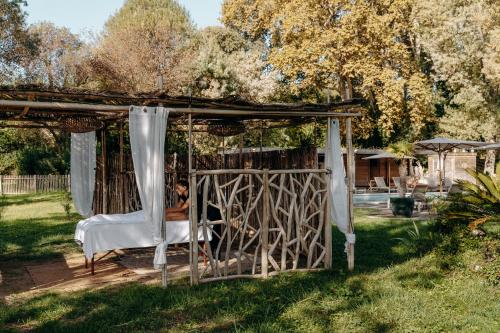 a woman sitting in a bed under a gazebo at Hôtel Domaine de Biar in Montpellier