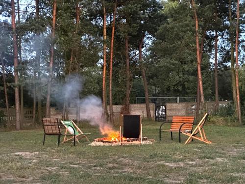 three chairs around a fire in a park at Apartamenty Rycerskie in Inowłódz