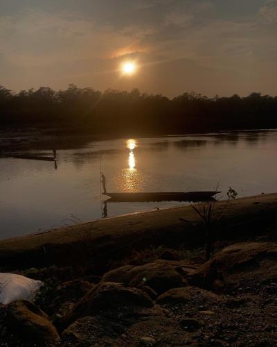 a boat on a river with the sunset in the background at BhupuSainik Guest House - Sauraha, Chitwan in Sauraha