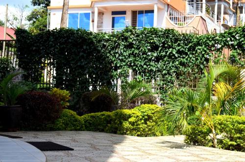 a garden with bushes and trees and a building at Hotel Top Five in Kampala