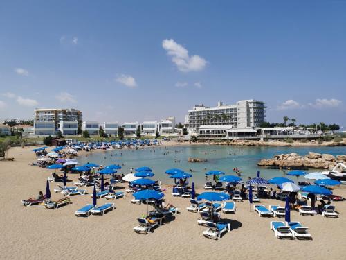 a beach with a bunch of chairs and umbrellas at Relax by the sea in Protaras