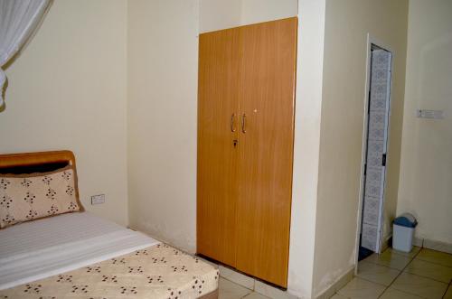 a bedroom with a bed and a wooden cabinet at Hotel Top Five in Kampala