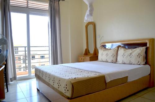 a bedroom with a bed and a large window at Hotel Top Five in Kampala