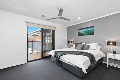a white bedroom with a bed and a balcony at Coastal Escape on Highlander in Torquay