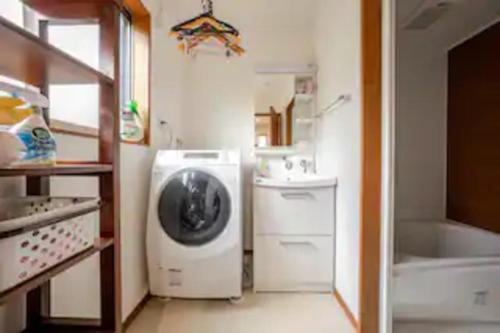 a bathroom with a washing machine and a bath tub at Kanazawa-Hachitabi konjiki in Kanazawa