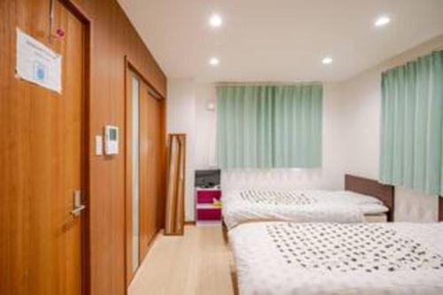 a hospital room with two beds and a door at Kanazawa-Hachitabi konjiki in Kanazawa