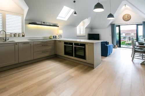 an open kitchen with wooden floors and white walls at Seashells Bracklesham Bay in Chichester