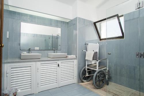 un bagno con due lavandini e una sedia a rotelle accanto a uno specchio di Casa dos Cães a Poço Partido