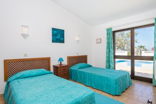 2 letti in una camera da letto con vista sulla piscina di Casa dos Cães a Poço Partido