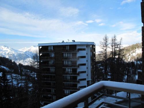 une vue d'un bâtiment avec des montagnes en arrière-plan dans l'établissement Appartement moderne à Plagne Centre avec balcon, 2 chambres et Wifi - FR-1-351-93, à La Plagne