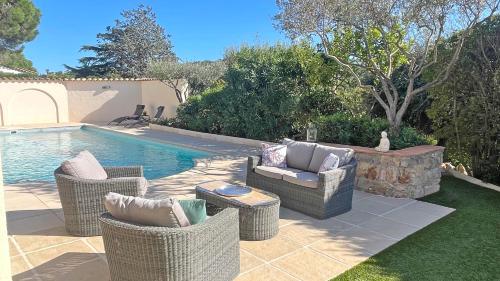 une terrasse avec des chaises en osier et une piscine dans l'établissement Villa Les Saquèdes, à Sainte-Maxime
