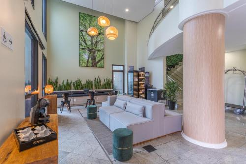 a living room with a white couch and a column at Green Place Ibirapuera in São Paulo