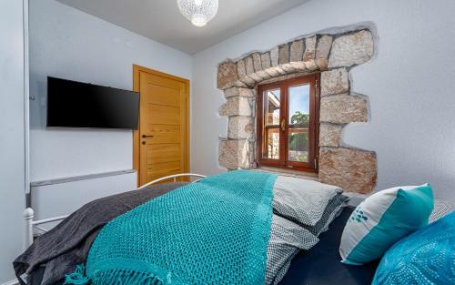 a bedroom with a bed and a tv on the wall at Rustic stone holiday house with pool in Marčana