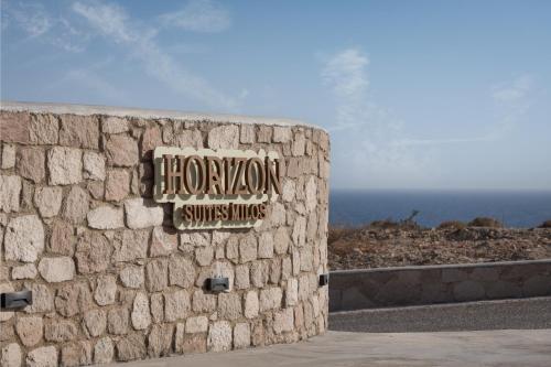 a sign for a hotel on a stone wall at Horizon Suites Milos in Paliochori