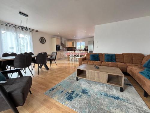 un salon avec un canapé et une table dans l'établissement La clé des champs Maison plain pied spacieuse lumineuse bien équipée, 3 chambres spacieuse, belle terrasse aménagée, garage, grand jardin clos, parking, près de Bayeux et Omaha Beach, à Tour-en-Bessin