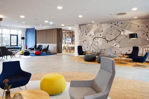 a lobby with chairs and a mural on the wall at Holiday Inn Express - Düsseldorf Airport in Düsseldorf